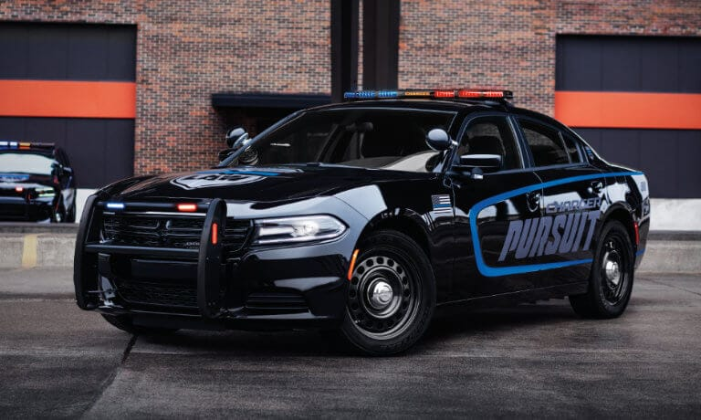 Black police pursuit vehicle parked in front of brick building