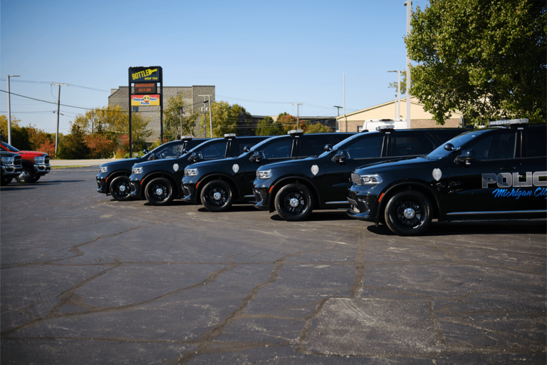 Row of black police SUVs parked in a lot on a sunny day