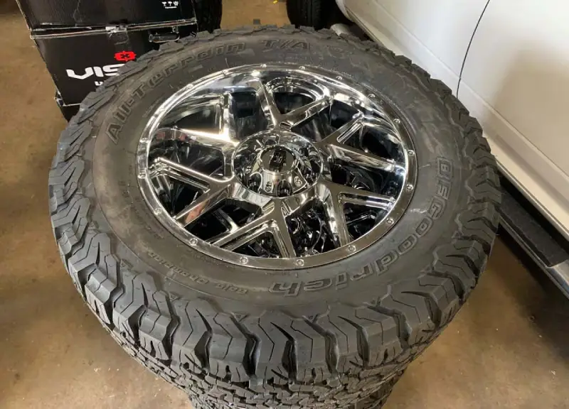 New BFGoodrich All-Terrain T/A mud tire with a shiny chrome custom rim, ready for installation.