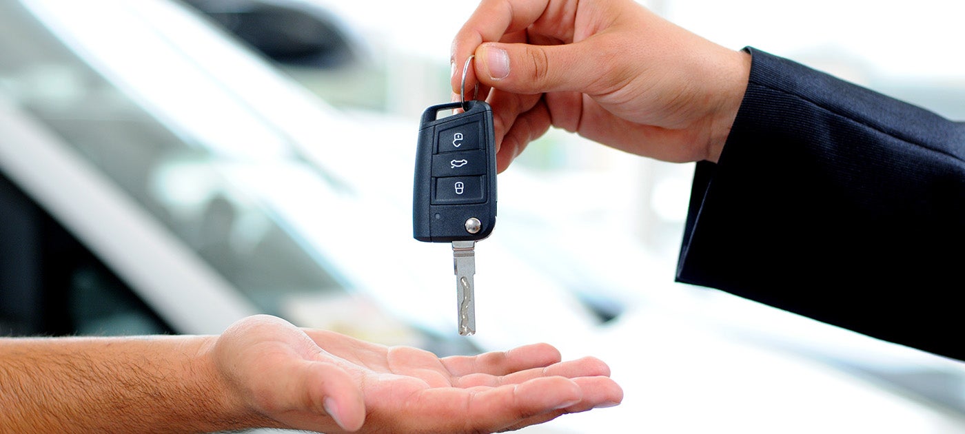 Person handing over car key to another person open hand